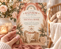 A person is holding a baby shower invitation with a baby's crib and a baby shower theme.