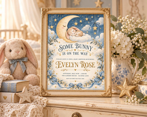 a framed baby shower invitation with a bunny and a crescent moon on it, placed on a dresser next to a stuffed bunny and some flowers.