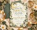 The image is a beautifully designed baby shower invitation featuring a moon and star motif, surrounded by greenery and flowers.