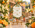 A baby shower invitation featuring a garden scene with orange trees and a sunset backdrop, surrounded by flowers and candles.