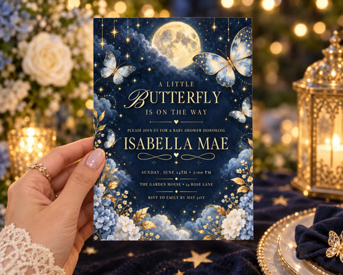 A hand holding a baby shower invitation with a night sky theme, featuring a full moon, butterflies, and flowers.