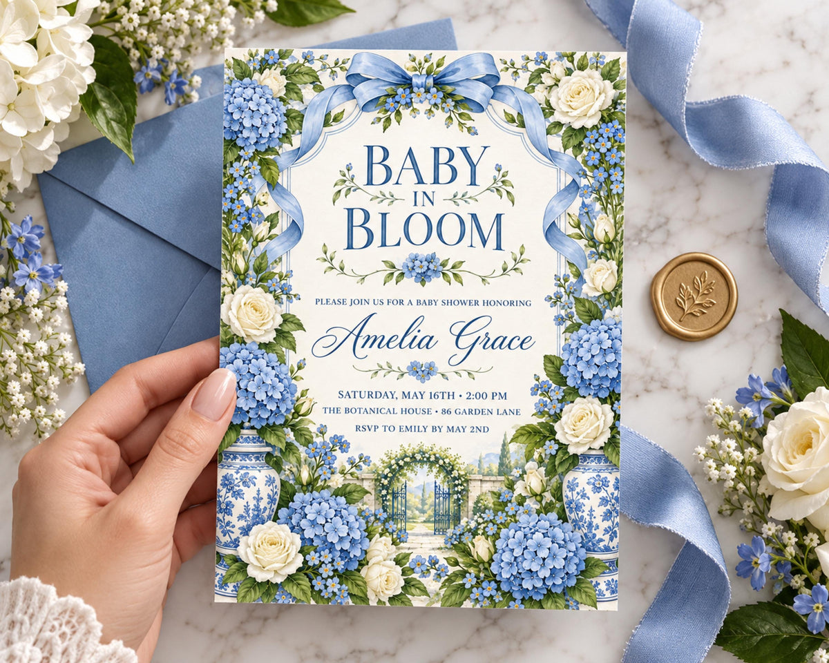 A hand holding a blue and white baby shower invitation with a floral design, surrounded by flowers and a ribbon.