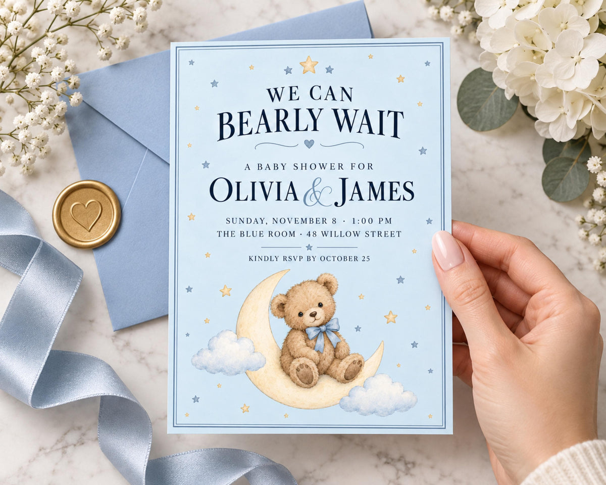 a hand holding a baby shower invitation card with a teddy bear on a crescent moon and stars design. The card is blue and has a gold seal and ribbon on the left side.