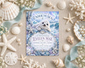 A baby shower invitation featuring a cute seal surrounded by seashells, pearls, and starfish, with a blue and white color scheme.