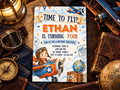 The image is a birthday invitation for a boy named Ethan, who is turning four years old. The invitation features a young boy riding a plane, surrounded by various aviation-themed items such as a globe, a model airplane, and a compass.