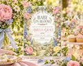 a beautifully decorated baby shower invitation with a floral design, surrounded by various desserts and flowers.