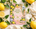 a pink invitation card with a lemon and flower design, surrounded by lemons, flowers, and a pair of scissors.