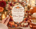 A hand holding a card with a pumpkin and fall-themed design, surrounded by other fall decorations.