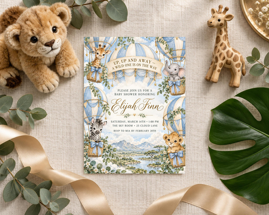 a baby shower invitation with illustrations of a lion, giraffe, and elephant, along with a landscape scene and a hot air balloon. The invitation is surrounded by plush toys, a ribbon, and some greenery.