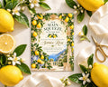 a lemon-themed invitation card with a scenic background of a lemon garden and a blue and white building, surrounded by fresh lemons, white flowers, and green leaves.
